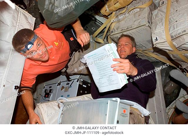 Astronauts Doug Wheelock (left) and Scott Parazynski, both STS-120 mission specialists, work among stowage bags on the middeck of Space Shuttle Discovery during...