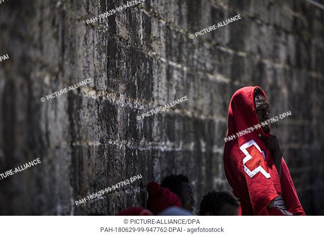 29 June 2018, Spain, Tarifa: An African migrant sit at the port of Tarifa covered in red blankets after being rescued from the Strait of Gibraltar