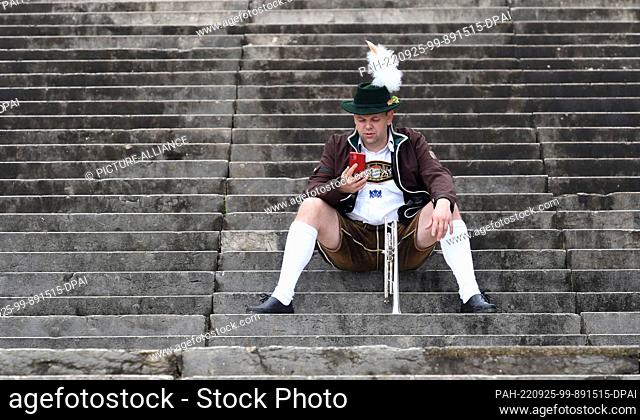 25 September 2022, Bavaria, Munich: Musician Andreas sits on the steps of the Bavaria at the Wiesnwirte 2022 square concert