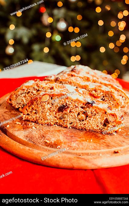 Christmas Stollen. Traditional Sweet Fruit Loaf with Icing Sugar. Xmas holiday table with stollen. Christmas tree in the room on the background