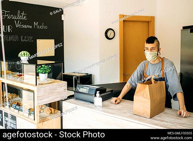 Young man with protective mask in cafe waiting for delivery man