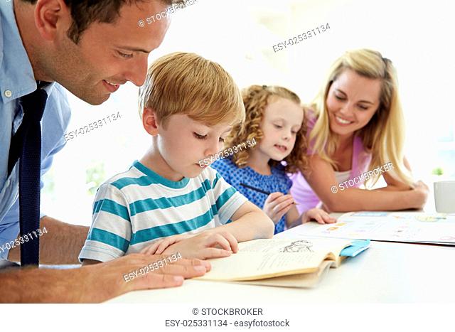 Parents Helping Children With Homework In Kitchen