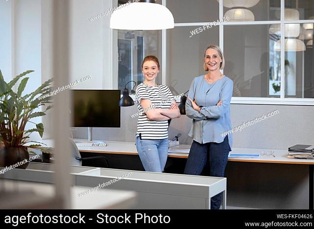 Confident businesswomen with arms crossed at office