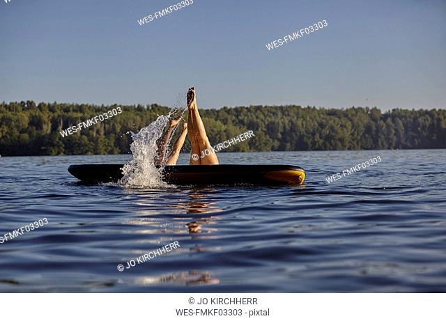 Two women jumping into water from paddleboard