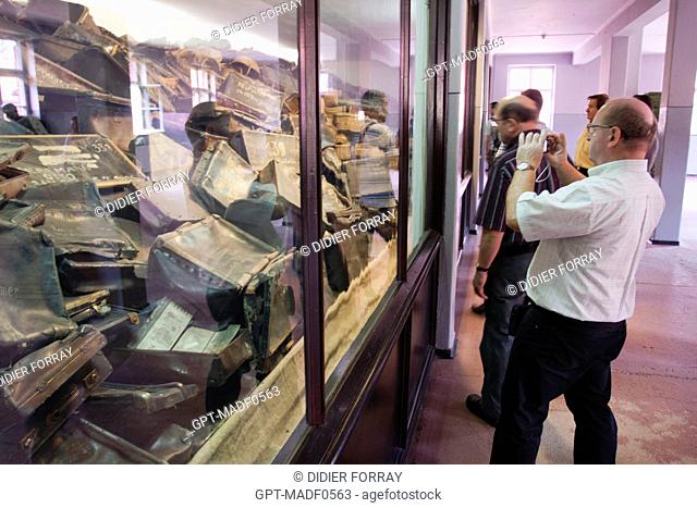 VISITORS IN FRONT OF THE PILE OF SUITCASES OF THE JEWS DEPORTED TO THE CONCENTRATION CAMP AUSCHWITZ I DURING THE SECOND WORLD WAR, BLOCK 5 AT KL AUSCHWITZ I