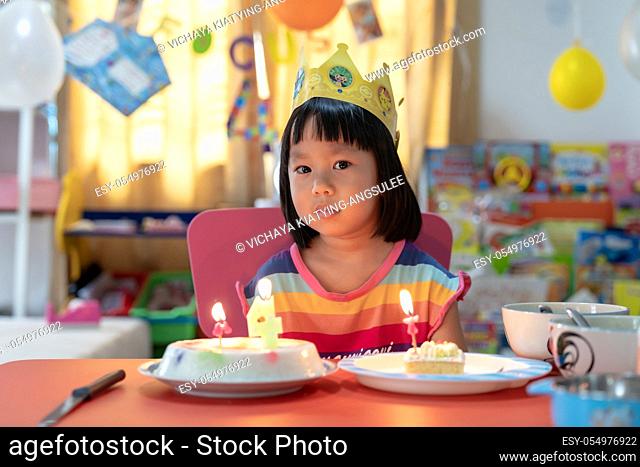 Asian girl kid with her birthday cake celebrate alone with family because city lockdown while COVID-19 Pandemic. Celbration and quarantine concept