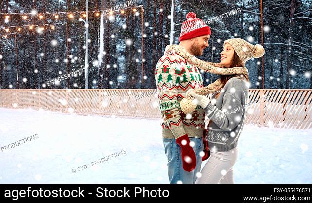 couple in ugly sweaters on christmas ice rink