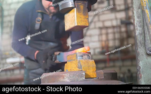 Automatic hammering - blacksmith forging red hot iron on anvil, extreme close-up, telephoto