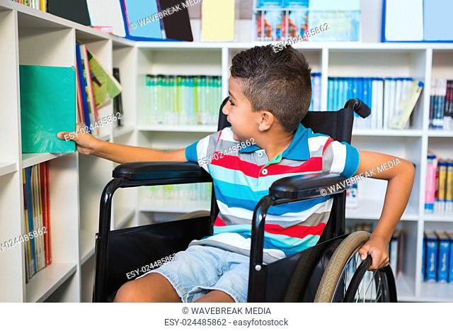 Disabled boy selecting a book from bookshelf in library