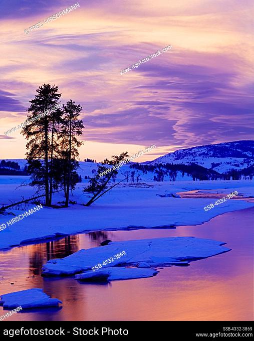 USA, Wyoming, Yellowstone National Park, Lamar Valley, Sunset light illuminating lenticular clouds beyond snowy banks of Lamar River