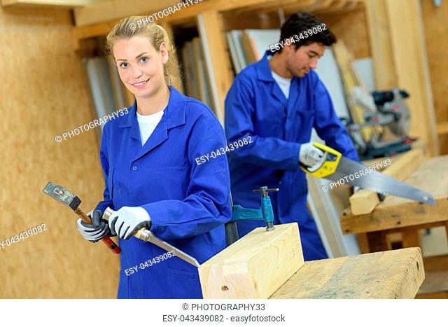 female carpenter posing for camara whilst chiseling wood