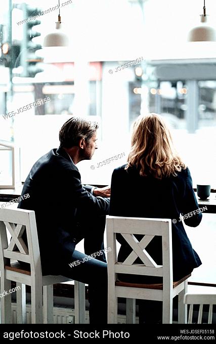 Male and female professionals discussing while sitting together in cafe