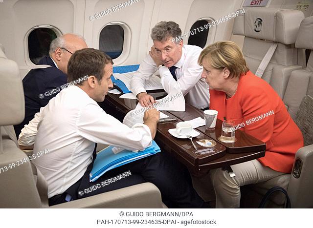 HANDOUT - Handout picture made available on 12 July 2017 showing German Chancellor Angela Merkel and French President Emmanuel Macron conversing on the way to...