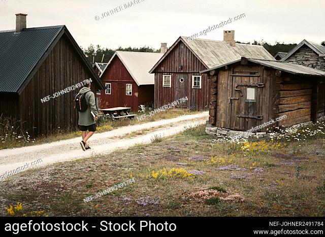 Man on dirt road leading to wooden houses