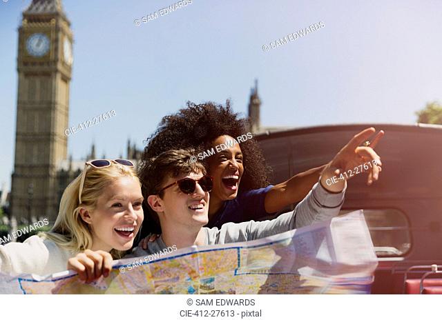 Enthusiastic friends with map below Big Ben clocktower in London