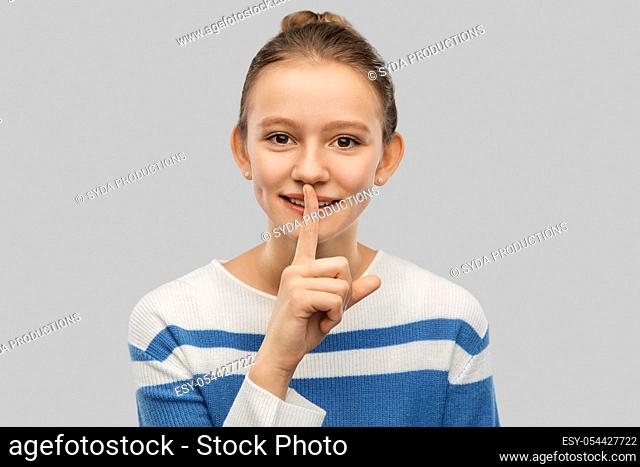 smiling teenage girl with finger on lips