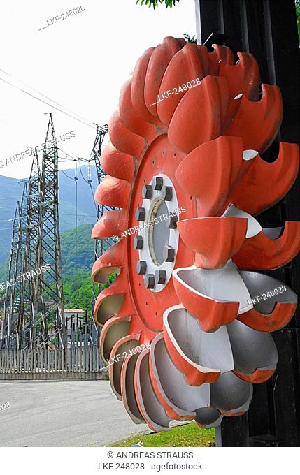 Turbine wheel with electricity pylons in the background, Pelton turbine, water power plant near Chiavenna, Ciavenna, Lombardy, Italy