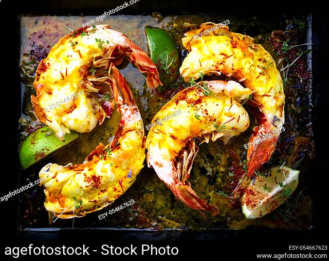 Traditional barbecue spiny lobster tail sliced and offered with saffron lemon sauce as top view on a metal tray
