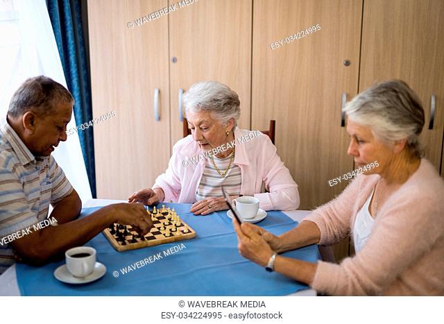 Senior friends playing chess and having coffee