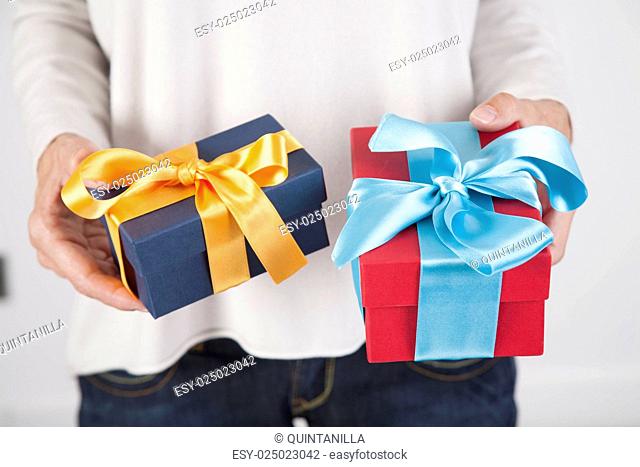 woman blue jeans cream jersey with two gift boxes in both hands, blue yellow and red cyan, over white background