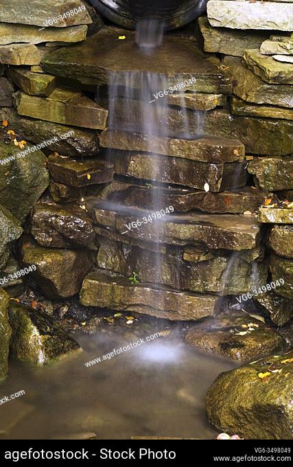 Close-up of natural stone man-made waterfall in a front yard country garden in summer