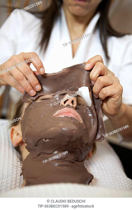 Beautician applying facial mask of chestnut musk