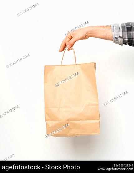 Man hand in plaid shirt twisted sleeve hand holding brown paper bag isolated on white background. Delivery concept. Paper bag for takeaway food
