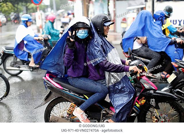 Heavy monsoon rain. Vietnamese people driving Motorbikes on Saigon Street. Ho Chi Minh City. Vietnam