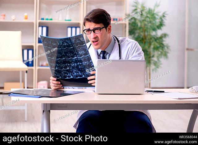 Young doctor looking at x-ray images in clinic