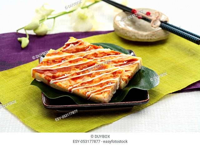 Real firmer okonomiyaki on green leaf and black plate in Japanese restaurant