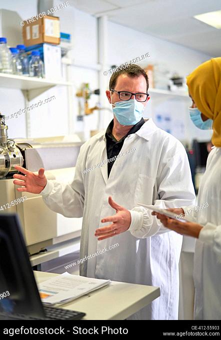 Scientists in face masks talking in laboratory