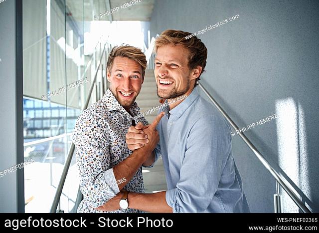 Portrait of two happy young businessmen shaking hands