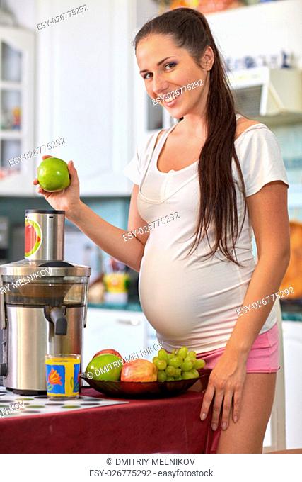 Beautiful pregnant woman with fresh fruit on the house kitchen