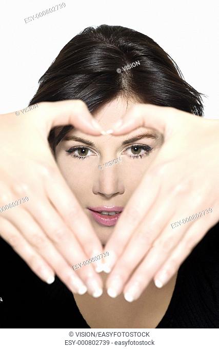 studio shot portrait on isolated white background of a Beautiful Woman gesturing heart shape with hands