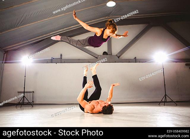 The theme of Acroyoga and Yoga Poses. Acroyogis practicing. with studio Backlight. the Base man tosses the Pops woman Flyer in flight up
