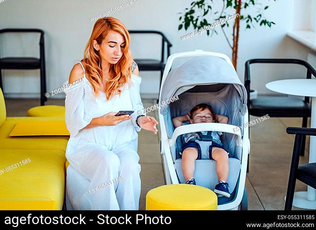 Portrait of a cute happy mom and stroller with her baby