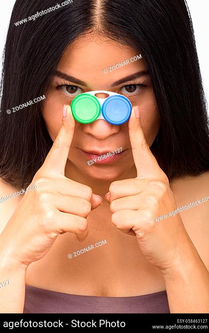 Picture of attractive woman with container for contact lenses. Korean or Asian lady looking at camera while holding case for contat lenses in studio