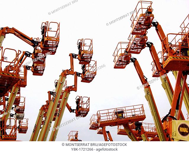 Industrial aerial work platforms facing eachother like getting into a clash against white background in Dordrecht, Zuid Holland, The Netherlands