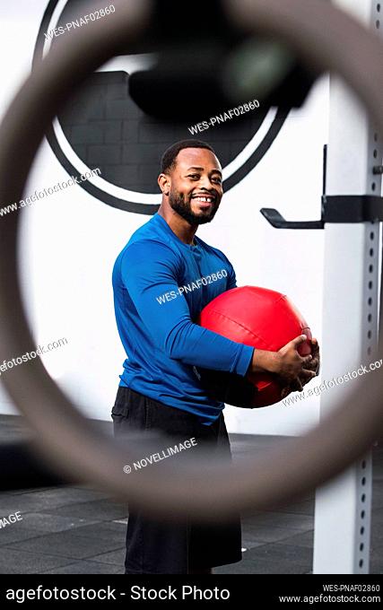 Smiling sportsman with medicine ball standing in gym