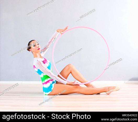 Portrait of flexible gymnast girl that doing acrobatic feat with pink hoop