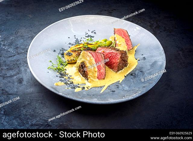 Modern style fried dry aged wagyu roast beef pepper steak with fennel and eggplant in pepper cream sauce served as close-up in a design plate