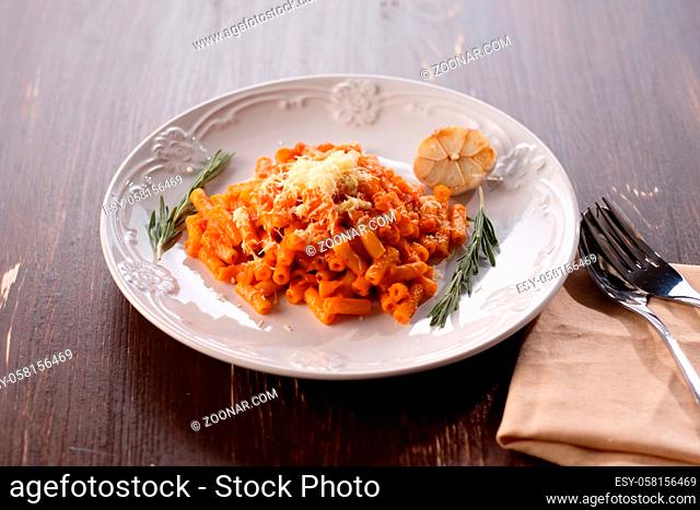 Italian pasta with tomato cheese and garlic. Close-up on a plate with melted cheese