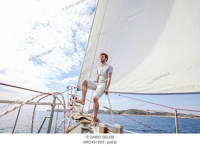 Man on bow of sailboat looking out over sea
