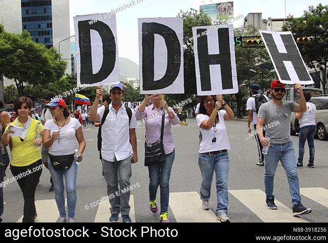 Protestors against dictatorship Nicolas Maduro hold up signs for human rights at a protest march in Caracas, Venezuela