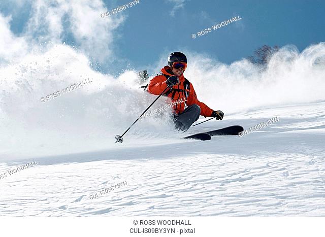 Male skier skiing down mountainside, low angle view, Alpe-d'Huez, Rhone-Alpes, France