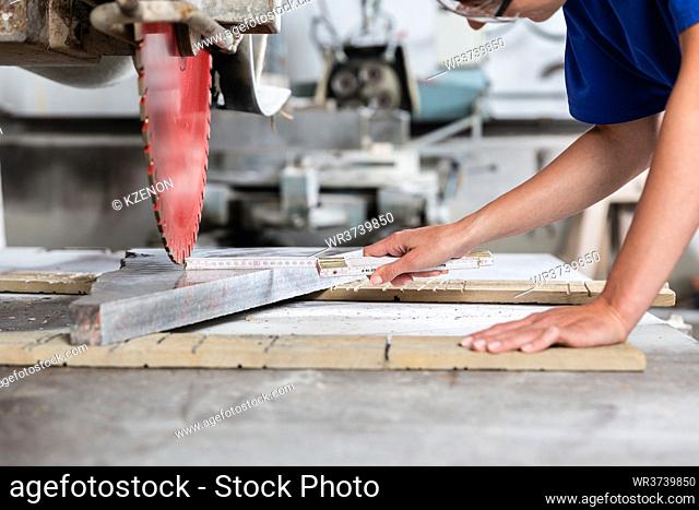 Stone mason woman measuring stone plate for sawing in workshop