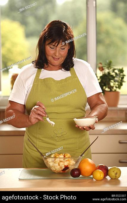 Woman prepares fruit salad with yoghurt, prepare, bowl, salad servers, spoon