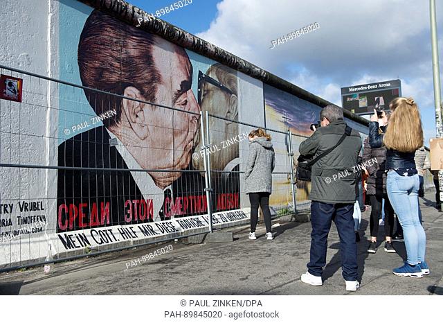 Tourists look at a mural entitled 'The Brother Kiss' depicting the general secretary of the East German SED (Socialist Unity Party) Erich Honecker and th...