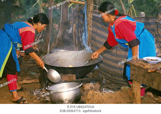 Lisu women stir frying a meal in a large wok for New Year dinner