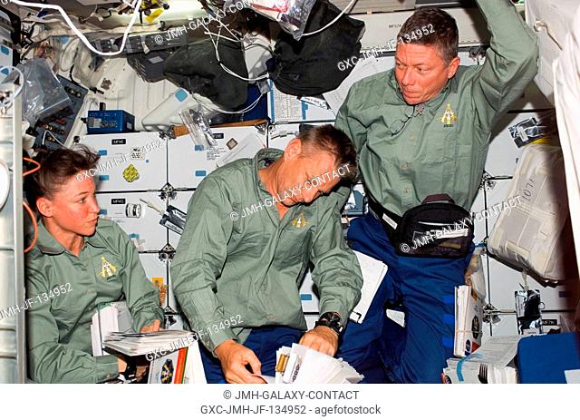 Astronauts Lisa M. Nowak (left), Piers J. Sellers and Michael E. Fossum, all STS-121 mission specialists, look over procedures checklists on the middeck of the...
